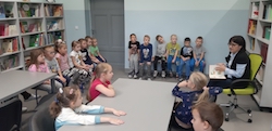 dzieci siedzą na ławkach w bibliotece