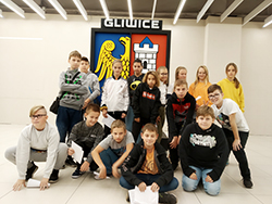 Grupa dzieci pozuje na tle godła zespołu Piat Gliwice