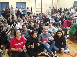Uczniowie siedzą na parkiecie w sali gimnastycznej