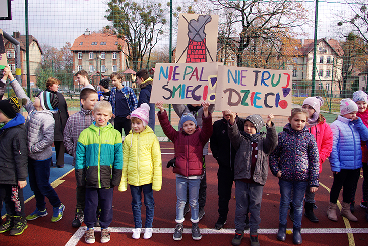 Uczniowie w kurtkach prezentują plakaty