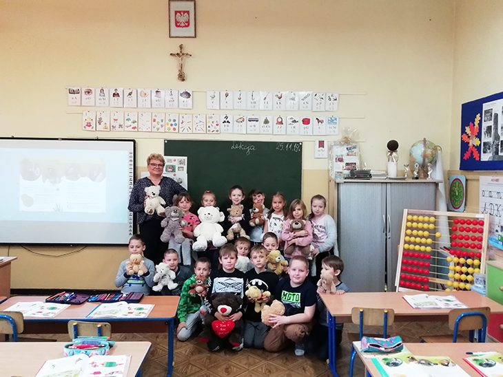 dzieci pozują w sali lekcyjnej z misiami