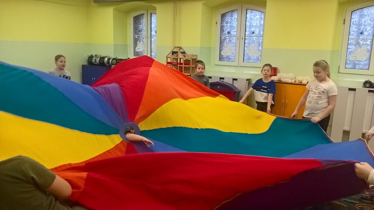 Dzieci trzymają kolorową tkaninę