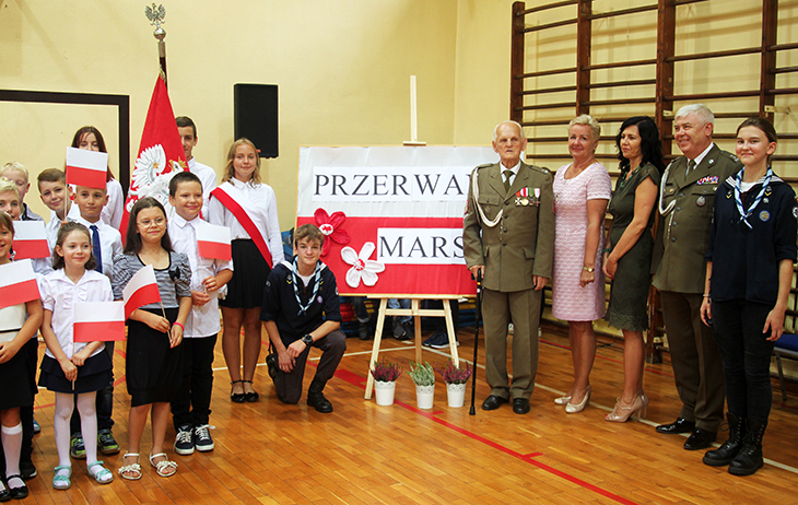 Pani Dyrektor wraz z kombatantami oraz dzieć mi pozuje na tle tablicy "Przerwany marsz"