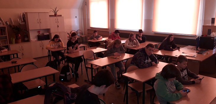 uczniowie siedzą w ławkach w sali lekcyjnej