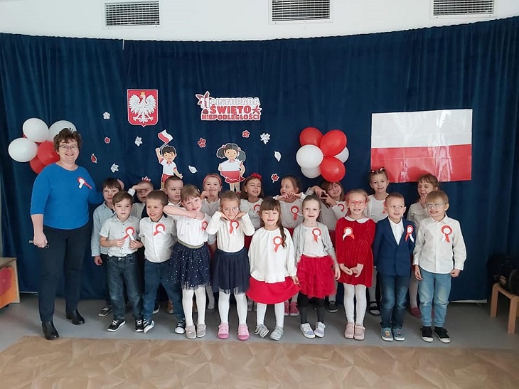 Dzieci z nauczycielami w udekorowanej w symbole narodowe sali