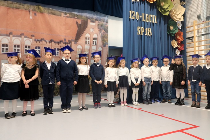 uczniowie klas pierwszych stoją w strojach galowych
