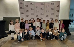 na zdjęciu grupa dzieci pozuje na tle ściany Teatru Miejskiego