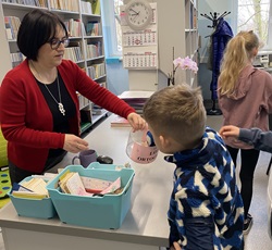 Bibliotekarka z dzieckiem w dniu obchodów języka ojczystego, zajęcia warsztatowe w bibliotece