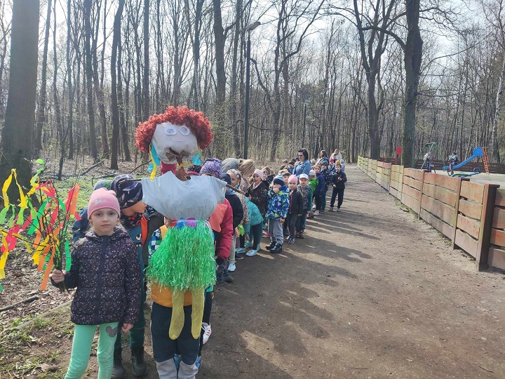 na zdjęciu sześć stoi sześć dziewczynek  na tle napisu wiosna.. dzieci mają kolorowe ubrania z bibuły