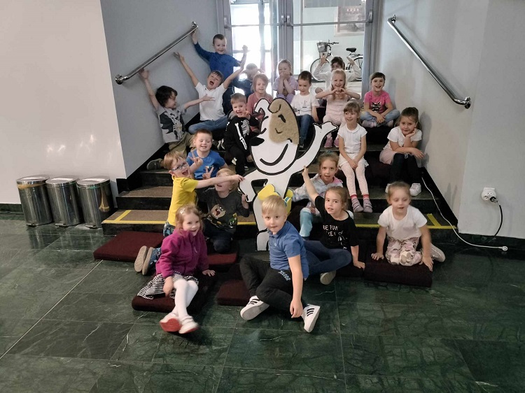 Za zdjęciu cała grupa dzieci siedzi na schodach w środku kina Amok