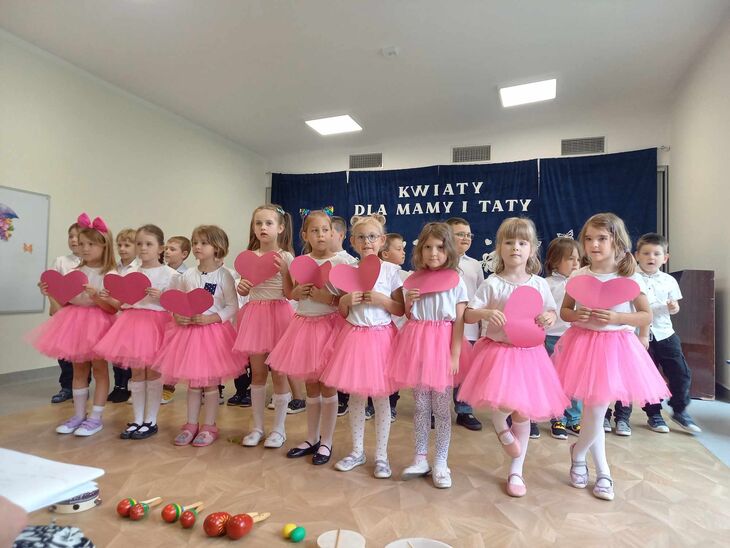 dzieci trzymają papierowe serca podczas występu z okazji dnia mamy i taty