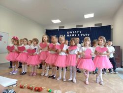 dzieci trzymają papierowe serca podczas występu z okazji dnia mamy i taty 
