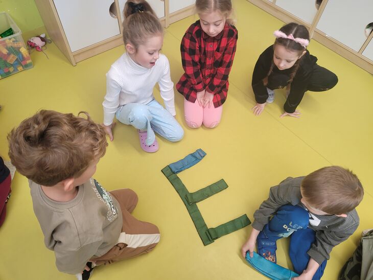 Grupa Iskierek układająca litery z szarf 