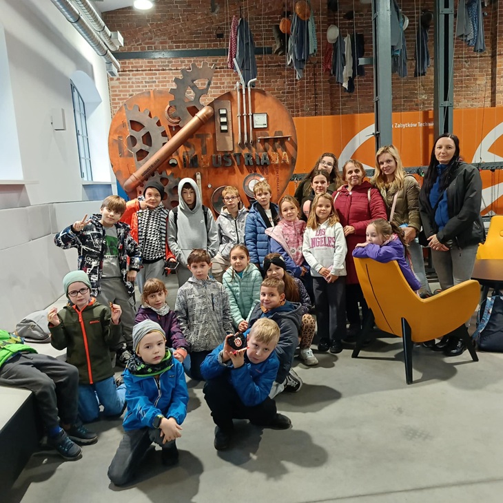 Na zdjęciu widać grupę uczniów wraz z opiekunami podczas wycieczki do sztolni „Królowa Luiza” w Zabrzu ⛏️. Uczniowie pozują wspólnie do pamiątkowego zdjęcia w nowoczesnym, industrialnym wnętrzu z elementami dawnej techniki i charakterystyczną metalową instalacją w tle ⚙️.