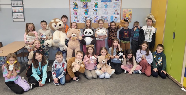 uczniowie stoją z misiami na tle szafy, wesoła gromada dzieci