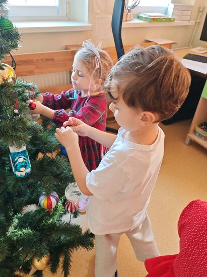 dzieci wieszają ozdoby na choince
