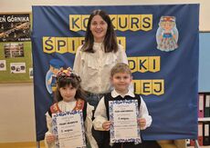 uśmiechnięta nauczycielka z dwójką dzieci ubranych w stroje ludowe - śląskie