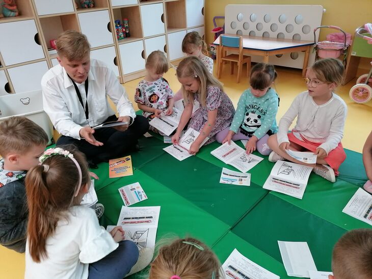 Dzieci oglądają materiały dydaktyczne rozdane przez konduktora