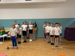 Na zdjęciu uczniowie klas 2 i 3 przygotowują się do zawodów sportowych w ramach szkolnego Tygodnia Zdrowia. Dzieci stoją w równych rzędach w sali gimnastycznej, gotowe do udziału w konkurencjach sprawnościowych.
