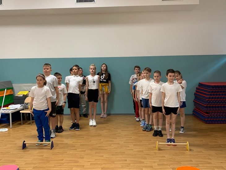 Na zdjęciu uczniowie klas 2 i 3 przygotowują się do zawodów sportowych w ramach szkolnego Tygodnia Zdrowia. Dzieci stoją w równych rzędach w sali gimnastycznej, gotowe do udziału w konkurencjach sprawnościowych.