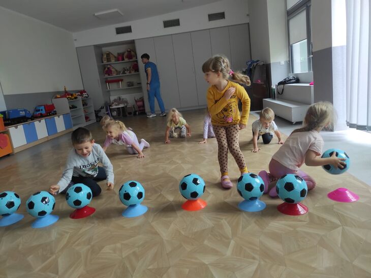 Dzieci ustawiające niebieskie piłki