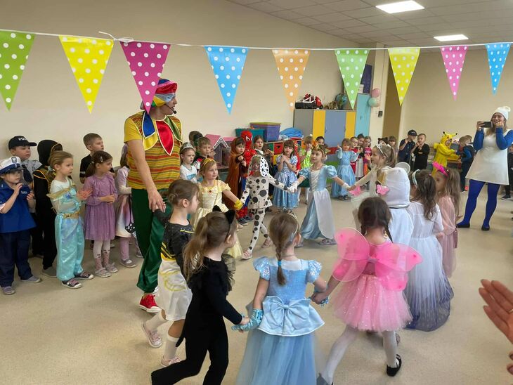 wesołe dzieci przebrane w karnawałowe stroje tańczące w kole za ręce