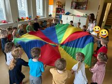 wesołe dzieci tańczące w kole przy kolorowej chuście klanzy