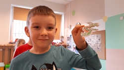 chłopiec prezentuje dinozaura naklejonego na klamerkę do ubrań