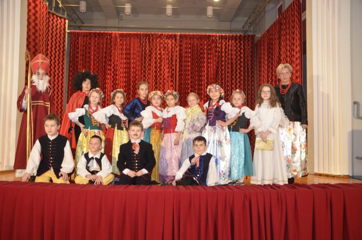 Grupa dzieci wraz z nauczycielka POZUJE NA SCENIE W STROJACH REGIONALNYCH