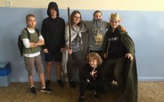 Uczniowie s wstrojach stacji literackich stoją przy ścianie